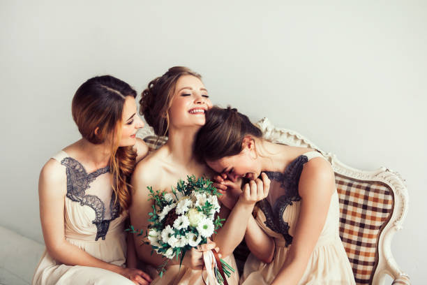 cheerful bride with her girlfriends sitting together stock photo