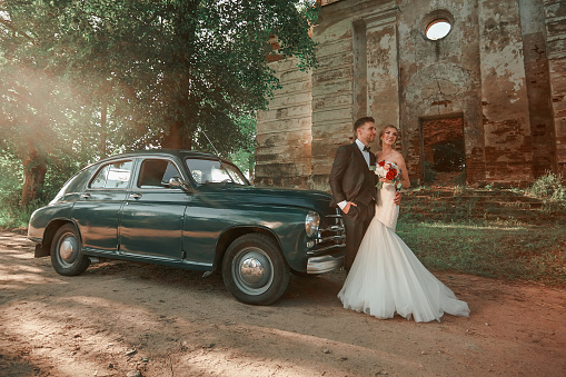 happy bride and groom, traveling by vintage car. wedding walk