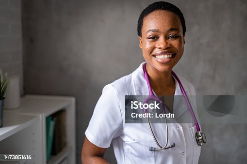 istock Portrait of a young smiling woman African-American ethnicity doctor standing with stethoscope in uniform at clinic 1473851616