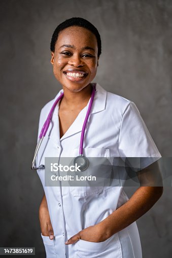 istock Portrait of a young smiling woman African-American ethnicity doctor standing with stethoscope in uniform at clinic 1473851619