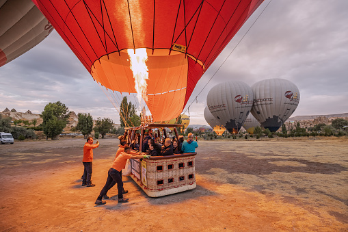 13 September 2022, Cappadocia, Turkey: Huge balloons warm up the air with burners before takeoff with tourists in baskets