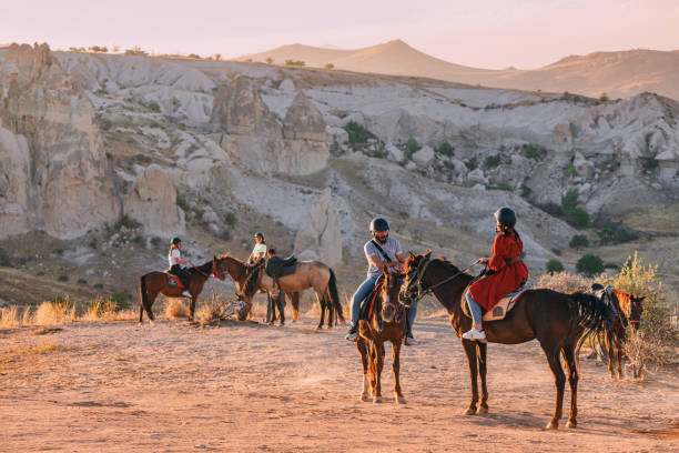 Group of tourists riding horses during excursion at sunset stock photo