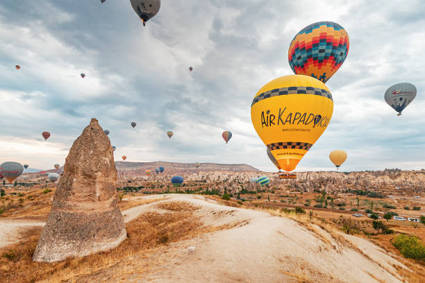 les montgolfières flottent sans effort sur un fond magnifique de formations rocheuses et de ciel nuageux. - dawn valley star morning photos et images de collection