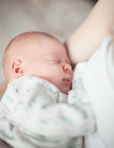 cute newborn baby sleeps in the arms of his mother. stock photo