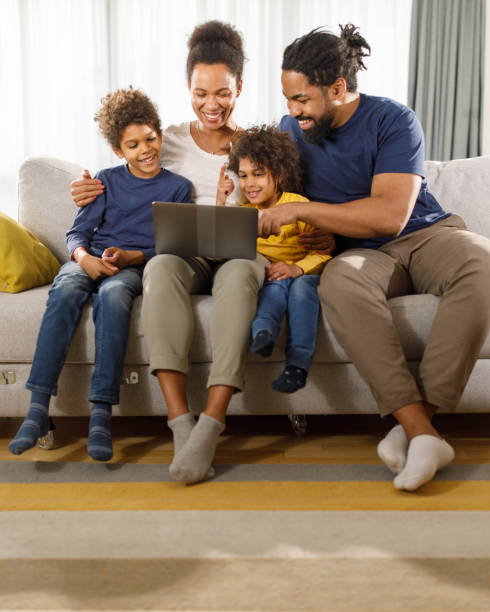 istock Happy black family using laptop on sofa at home. 1473854167