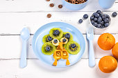 Peacock waffle for children's breakfast on a white wooden background. Adorable art food for kids in the shape of animals.