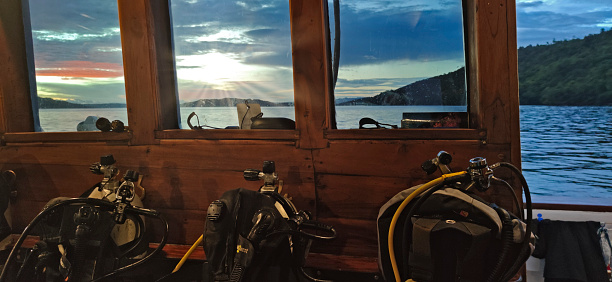 Scuba gear on the deck of a wooden boat sailing in a tropical paradise