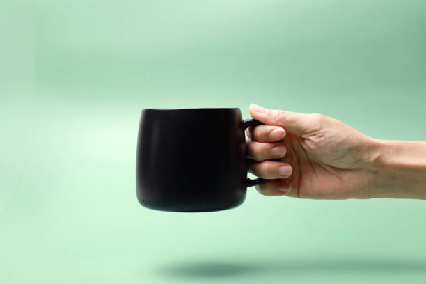istock Hand holding black ceramic mug on green background 1473856502