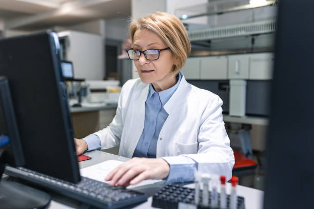 istock Female Scientists Working on their Computers In Big Modern Laboratory. Various Shelves with Beakers, Chemicals and Different Technical Equipment is Visible. 1473856620
