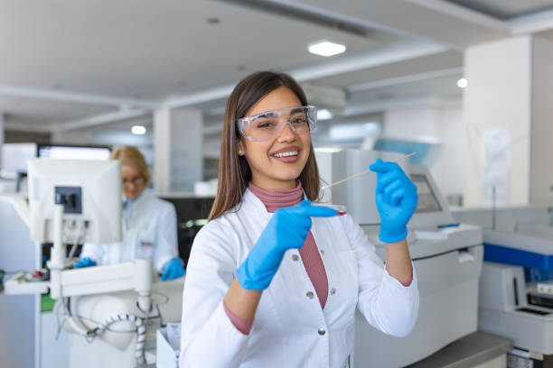 petrischale in der hand eines jungen wissenschaftlers in der nähe des mikroskops im labor. untersuchung der bakterienkulturplatte durch eine forscherin im mikrobiologischen labor - mikrobiologe stock-fotos und bilder