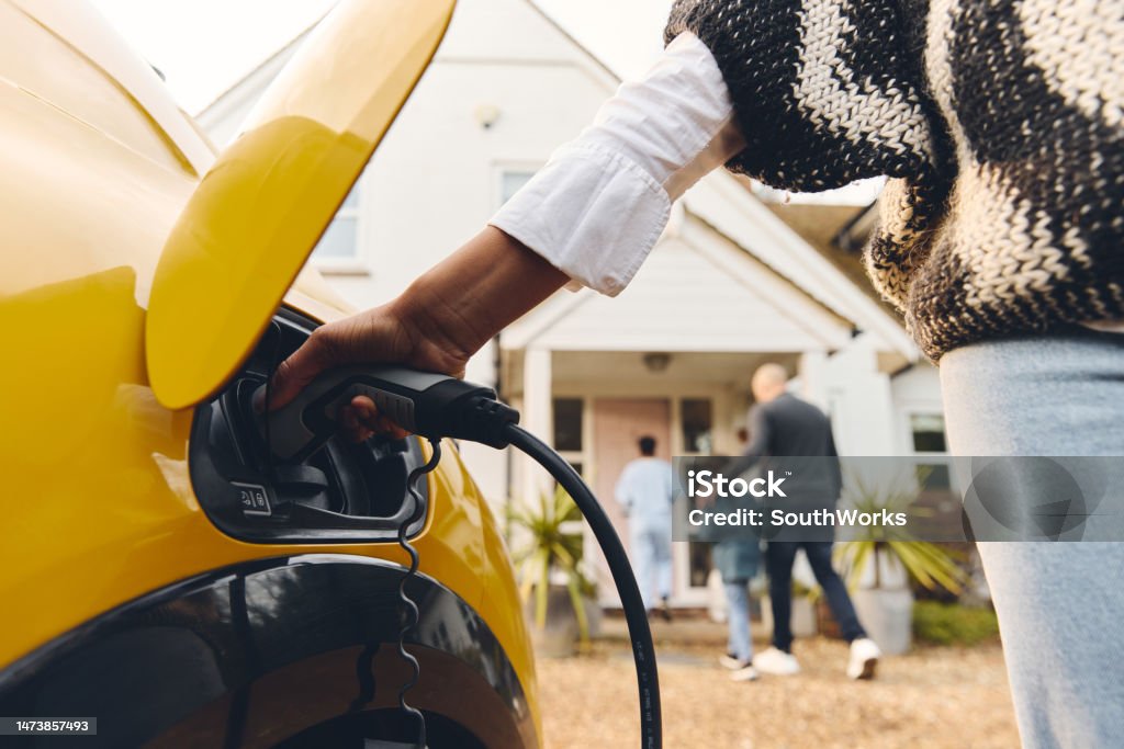 Woman plugging electric charger into car Electric Vehicle Stock Photo