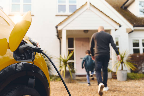 istock Electric car charging on driveway outside house 1473857496