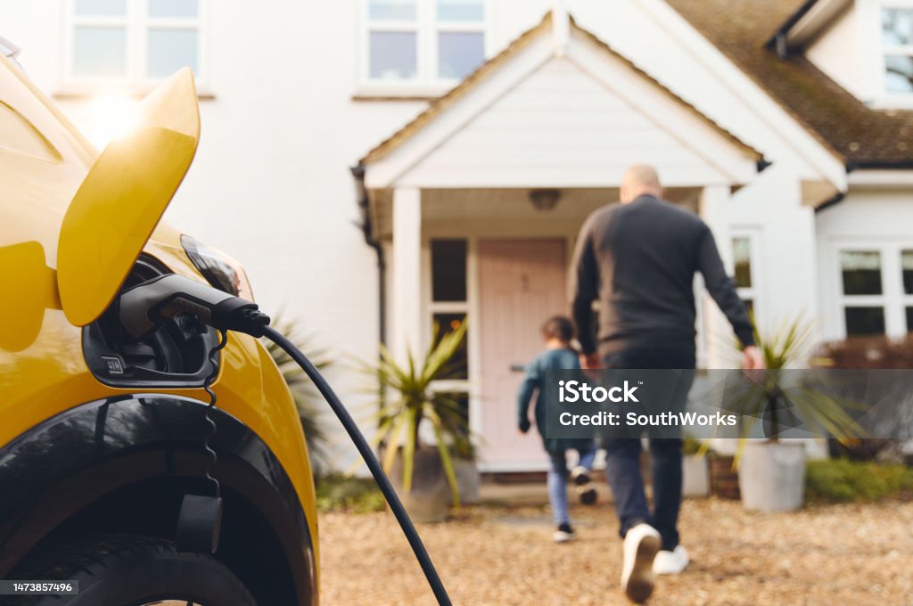 Electric car charging on driveway outside house Electric Vehicle Stock Photo