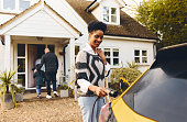 Woman plugging in electric charger into car