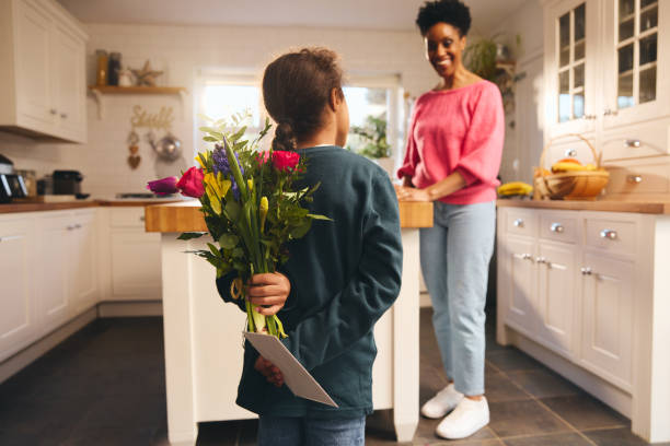 Boy hiding bouquet and card behind back on Mother's Day