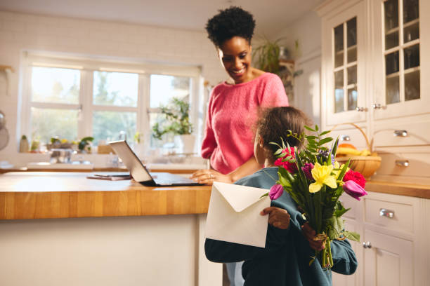 istock Boy giving mother bouquet and Mother's Day card 1473857504