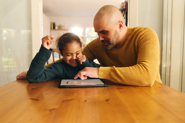 istock Multiracial father and son with Down syndrome using digital tablet for homework 1473857526