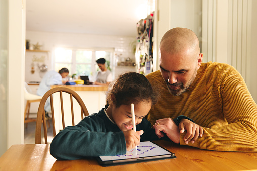 Multiracial father and son with Down syndrome using digital tablet