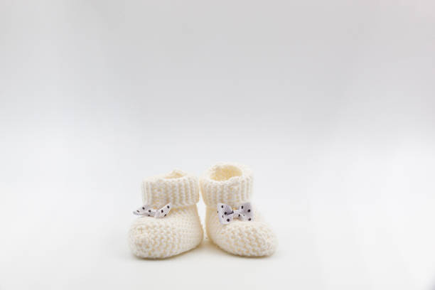 istock White knitted baby booties with bows on a gray isolated background 1473859783