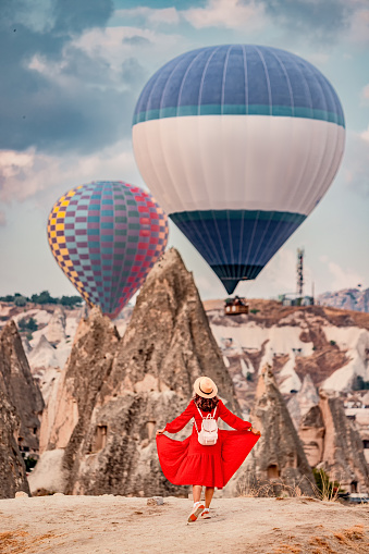 Mesmerised by the floating air balloons, the girl remained still as if in a trance, her dress a vibrant red against the orange sandstone of Cappadocia.