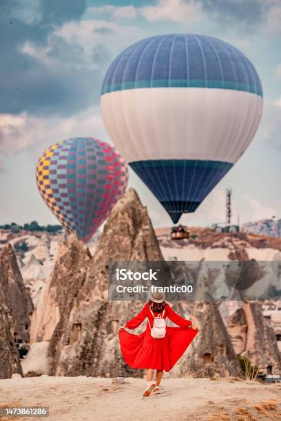 Mesmerised By The Floating Air Balloons The Girl Remained Still As If In A Trance Her Dress A Vibrant Red Against The Orange Sandstone Of Cappadocia Stock Photo - Download Image Now