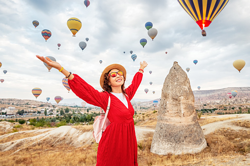 A girl in a dress absorbed in the breathtaking sight of flying hot air balloons in Cappadocia, the traveler's paradise.