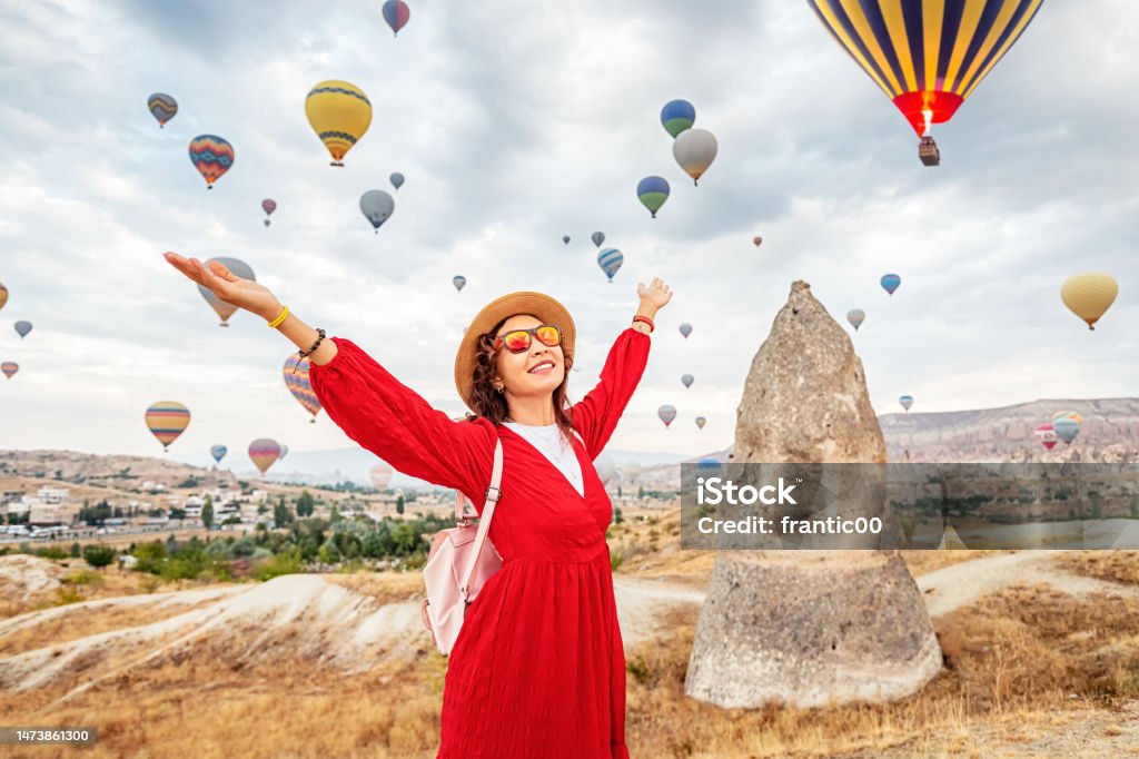 A girl in a dress absorbed in the breathtaking sight of flying hot air balloons in Cappadocia, the traveler's paradise. 30-34 Years Stock Photo