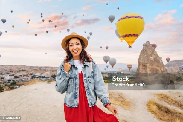 Girl Traveler In Her Dress Takes A Breath Of Desert Air Among The Colorful Balloons Drifting Through The Cappadocia Sky Basking In Their Beauty She Watches With A Wide Smile Stock Photo - Download Image Now