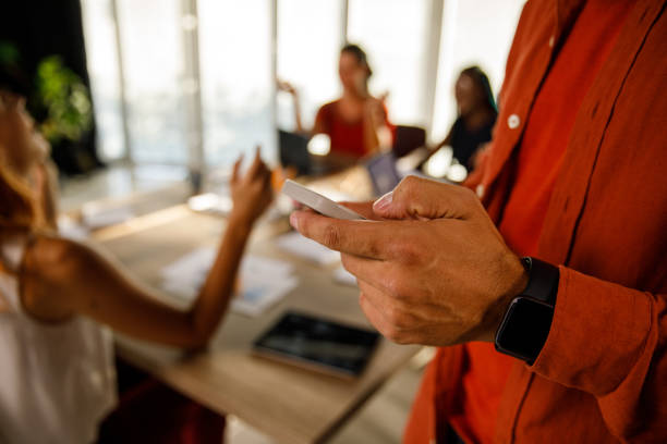 istock Businessman standing in a modern office, responding to a text message via smart phone 1473862706