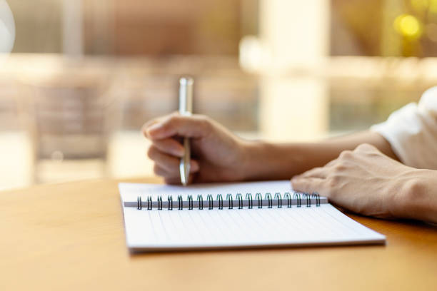 A close up of handwriting on lined paper with a pencil point in focus