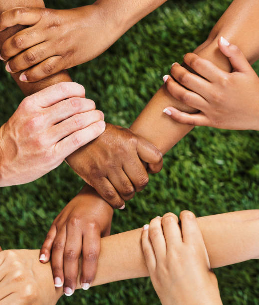 istock Diverse group of people with hands, wrists and arms interlinked, representing solidarity and teamwork 1473865938