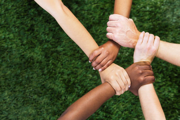 Diverse group of people with hands, wrists and arms interlinked, representing solidarity and teamwork stock photo