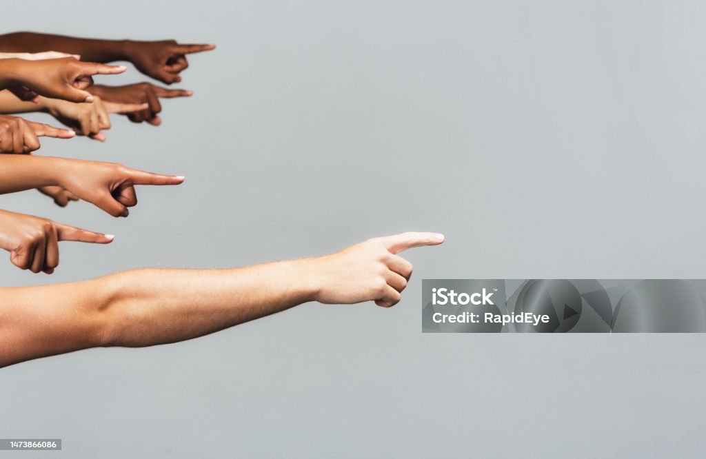 Diverse group of people all pointing to the right, with copy space, on gray background People with their arms outstretched, pointing as if to show the way. Blame Stock Photo