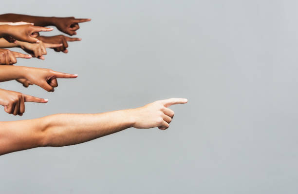 Diverse group of people all pointing to the right, with copy space, on gray background stock photo
