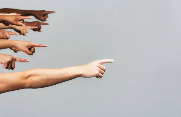 Photo of Diverse group of people all pointing to the right, with copy space, on gray background