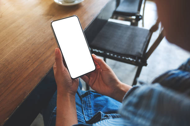 istock Mockup image of a woman holding mobile phone with blank white desktop screen 1473866219