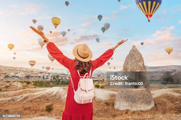 On A Summer Day In Cappadocia Turkey The Girl In Her Pretty Dress Finds Herself Mesmerized By The Elegant Sight Of Air Balloons In The Sky Stock Photo - Download Image Now