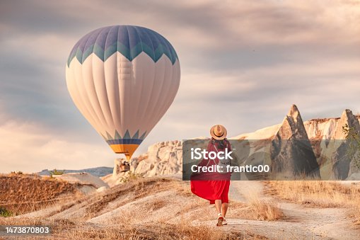 istock The air was alive with the sight of the balloons hovering in the sky above, and the girl below them in her red dress shining in the sunlight. She stood there, captivated. 1473870803