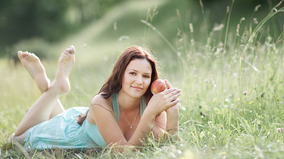 Young beautiful woman with Apple resting on fresh green grass .photo with copy space