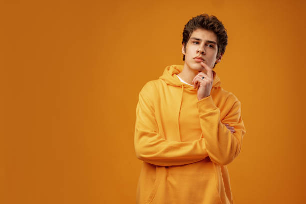 istock Young man thinking about things on yellow background 1473871834
