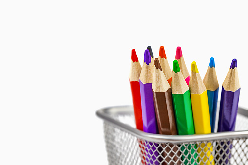 colored pencils in a metal stand on a light background with a place for text