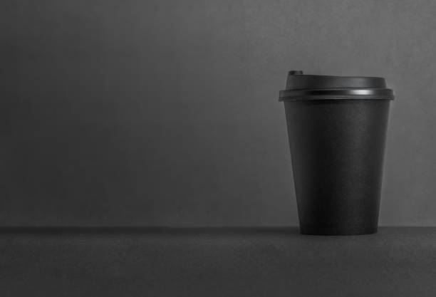 istock Black background take away paper coffee cup with copy space. 1473873742
