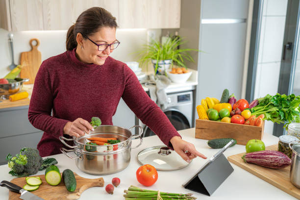 istock Woman using digital tablet and cooking vegetables in a steamer 1473875029