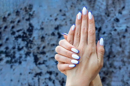 Color French manicure white ombre on the nails with blue stripes on the tips.