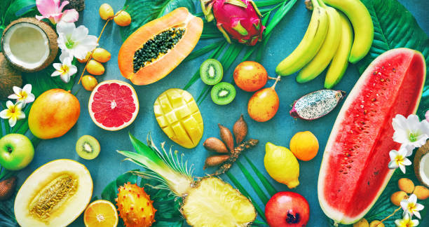 Assortment of tropical fruits with palm leaves and exotic flowers Assortment of tropical fruits with palm leaves and exotic flowers. Top view dragon fruit flower stock pictures, royalty-free photos & images
