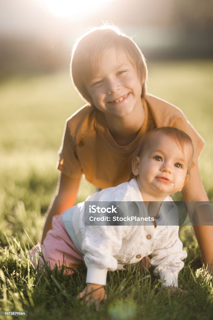 Happy siblings enjoying in nature Happy boy and his baby sister spending day in public park Child Stock Photo