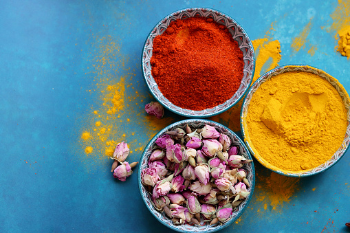 Still life with different spices on blue background with copy space. Vivid colors of food seasonings. Healthy eating concept.
