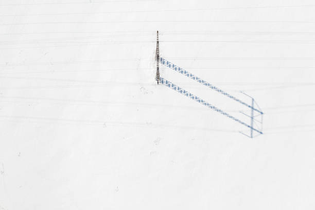 A single pylon of a power line in a snow covered field in winter.