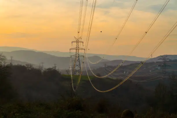 Photo of High-voltage power lines at sunset. Electricity distribution station. High voltage electric transmission tower.