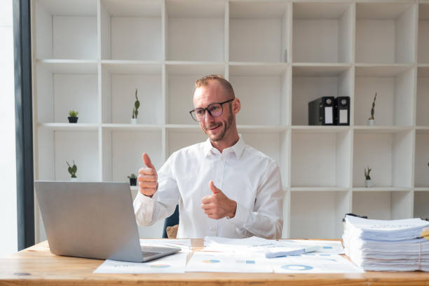 istock Handsome business man working using computer and paper happy with big smile doing, thumb up with fingers, excellent sign 1473883057